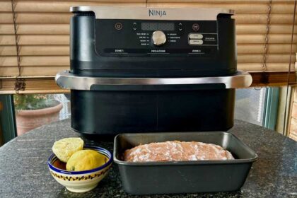 Ninja air fryer with a loaf cake in a tine in front of it