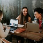 Three women with laptops laughing.