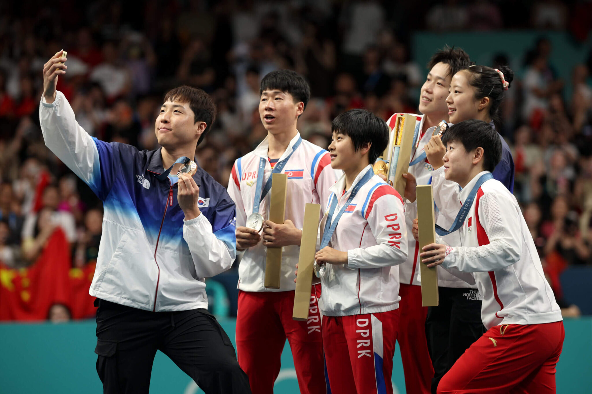 Olympic table tennis medalists from North and South Korea pose for a shared selfie