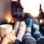 Two people in cosy socks watching TV with a cup of coffee