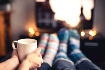 Two people in cosy socks watching TV with a cup of coffee